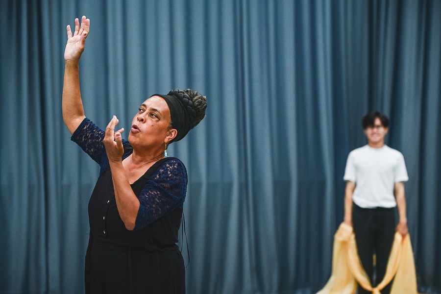 June choreographing, hands in air as she explains something to a dancer behind her.