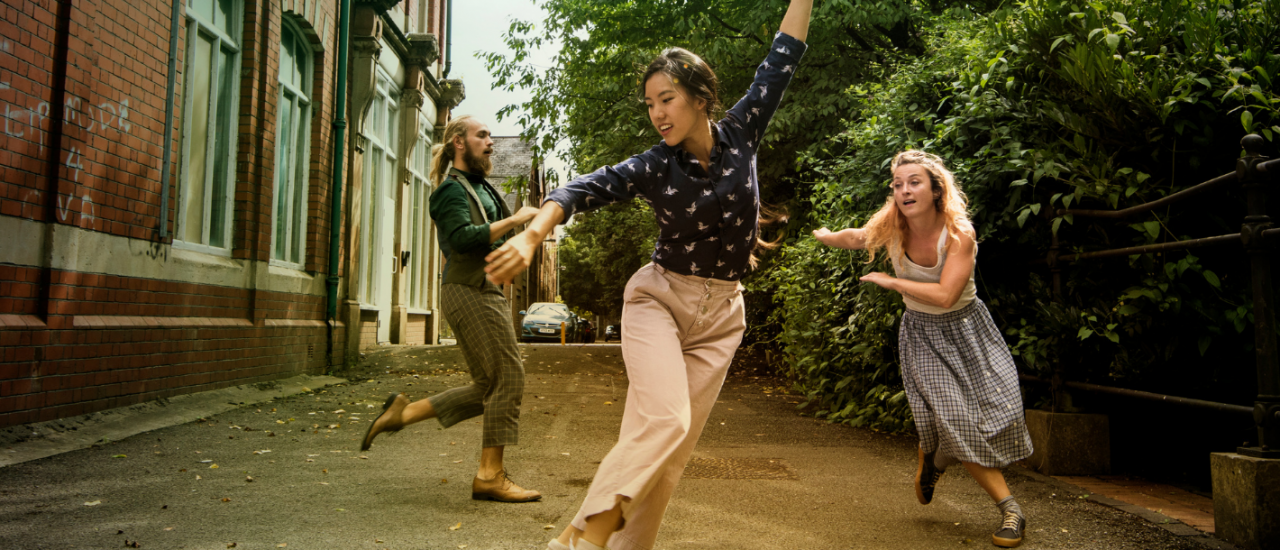 3 dancers outside smiling under blue skies