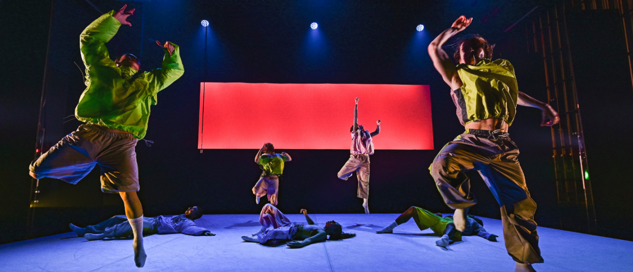 dancers in neon green leaping across a red backdrop