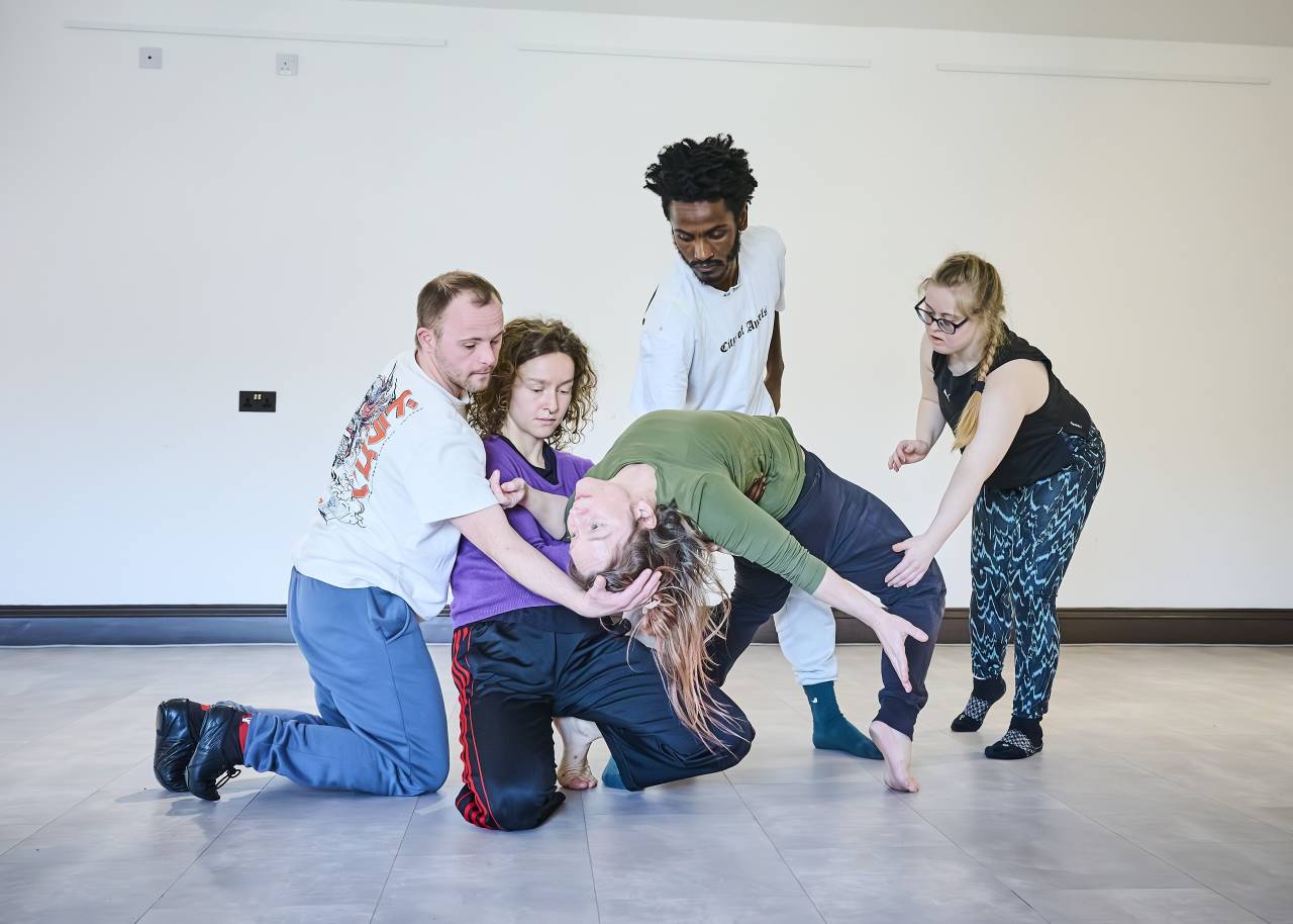 one dancer falls backwards, four others support them