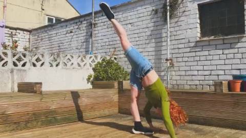 Dancer Camille in her own garden mid dancing, doing a standing splits 