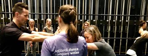 Person with purple NDCWales tshirt on observing two people doing a movement exercise