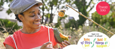 a smiling gardener poses with a stuffed bird and knitted bee 