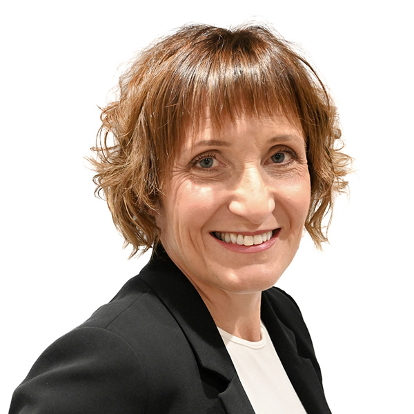 ceri has a warm smile, short brown flicky smart hair and wears a black blazer over white t shirt