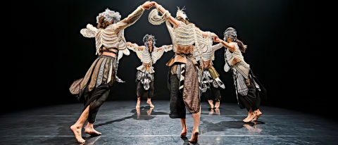 dancers in Osian Meilir's Mabon wear skeleton string vests and dance in a circle, arms raised in celebration